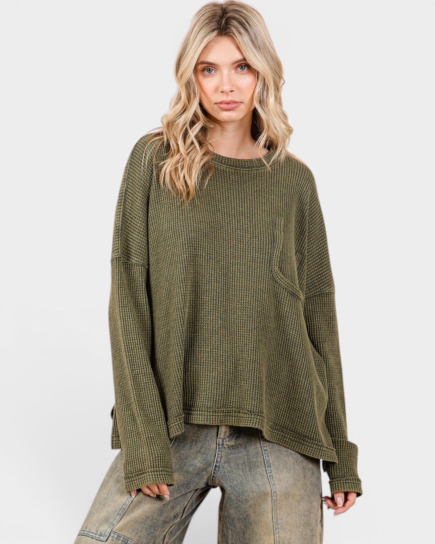 Woman wearing an olive green waffle knit sweater on a white background
