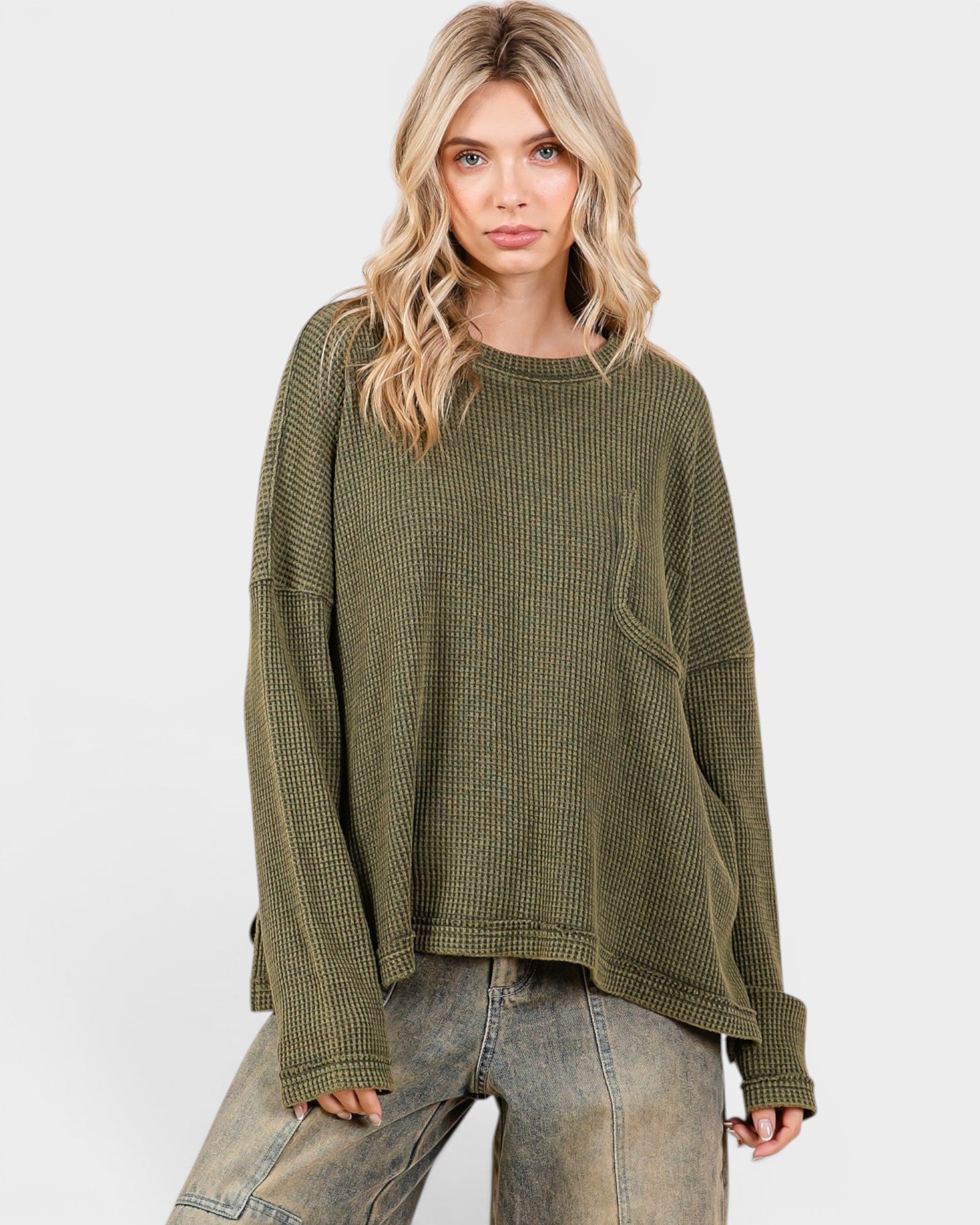 Woman wearing an olive green waffle knit sweater on a white background