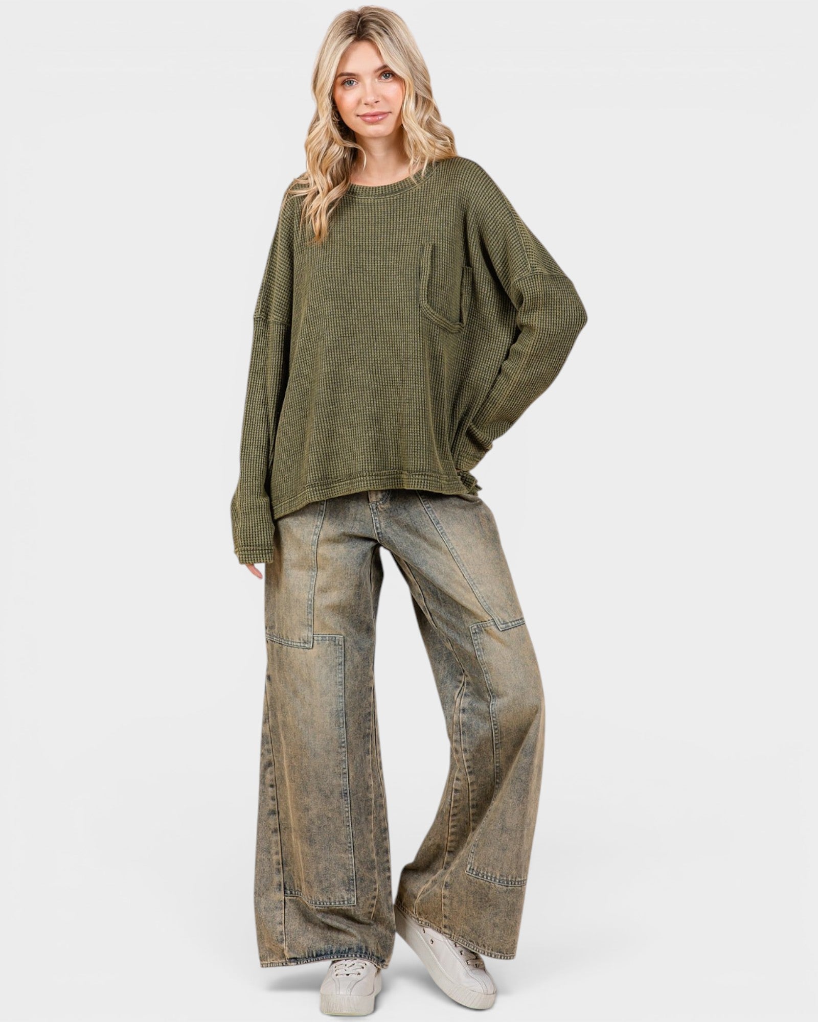 Woman wearing a green sweater and wide-leg jeans on a white background