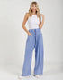 Woman wearing light blue wide-leg pants and a white top on a white background
