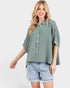 Woman wearing a green plaid shirt and denim shorts on a white background
