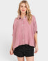 Woman wearing a pink plaid shirt and black shorts on a white background