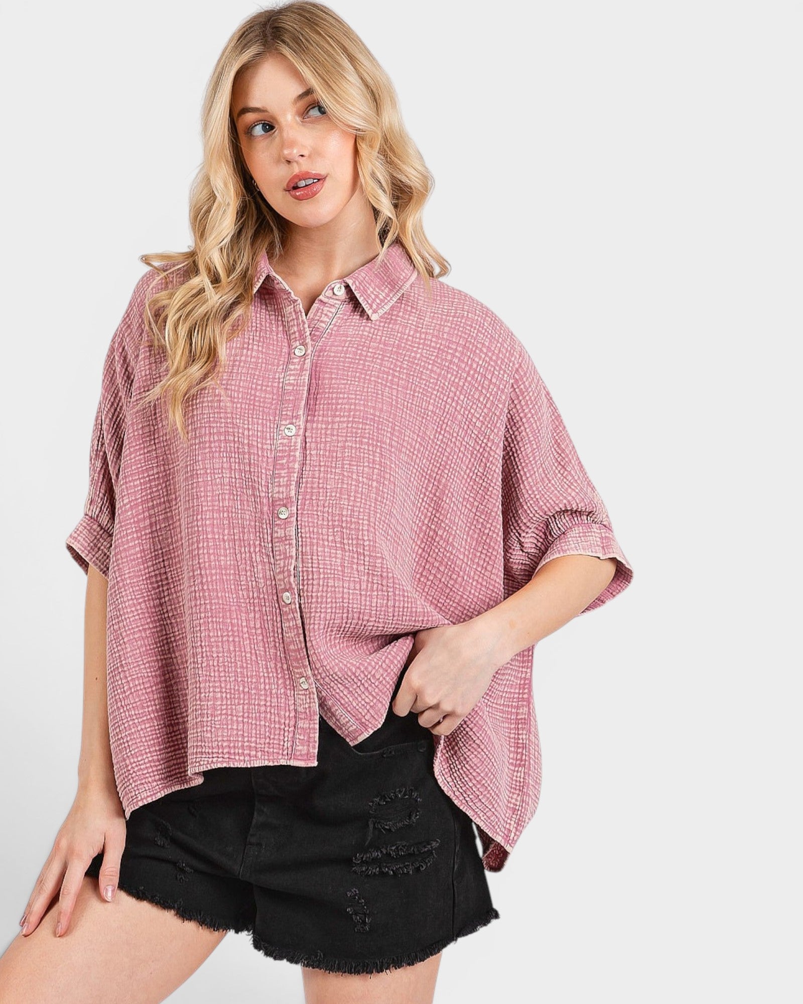 Woman wearing a pink plaid shirt and black shorts on a white background