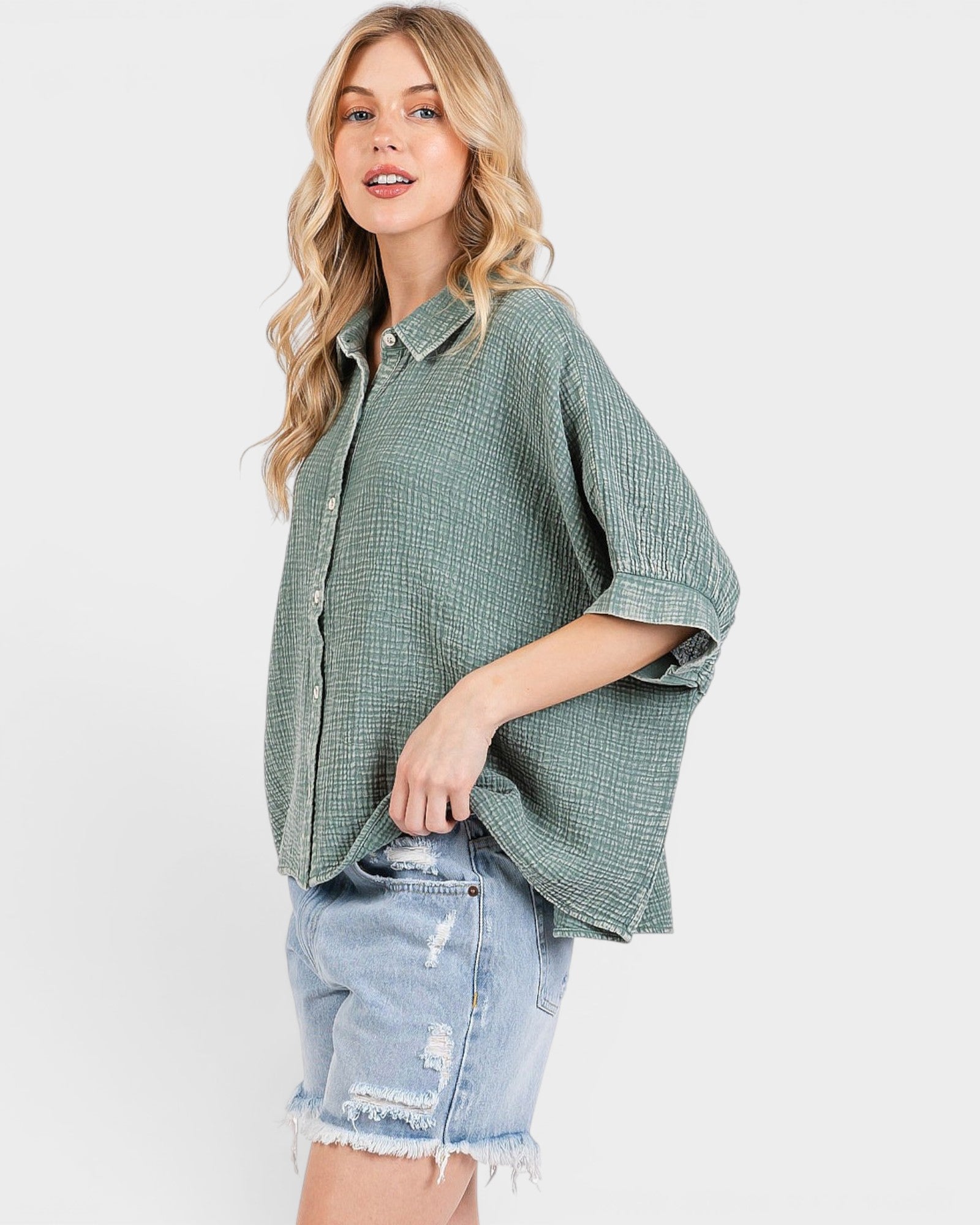 Woman wearing a green checkered shirt and denim shorts on a white background