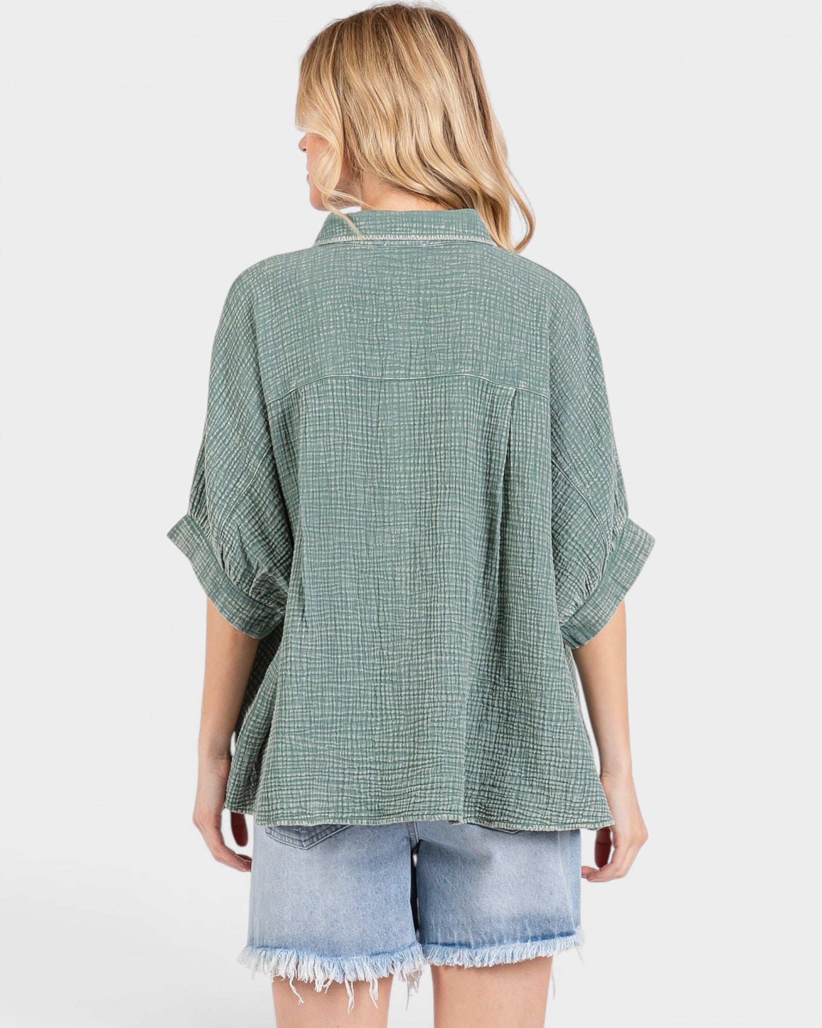 Woman wearing a green checkered shirt and denim shorts on a white background