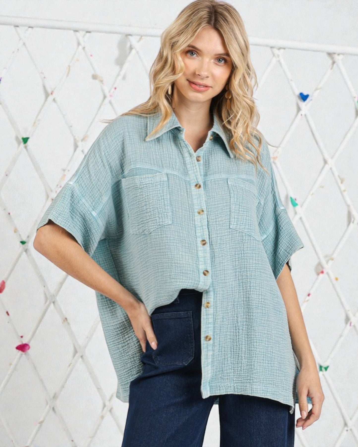 Woman wearing a light blue checkered shirt with a white geometric patterned wall in the background
