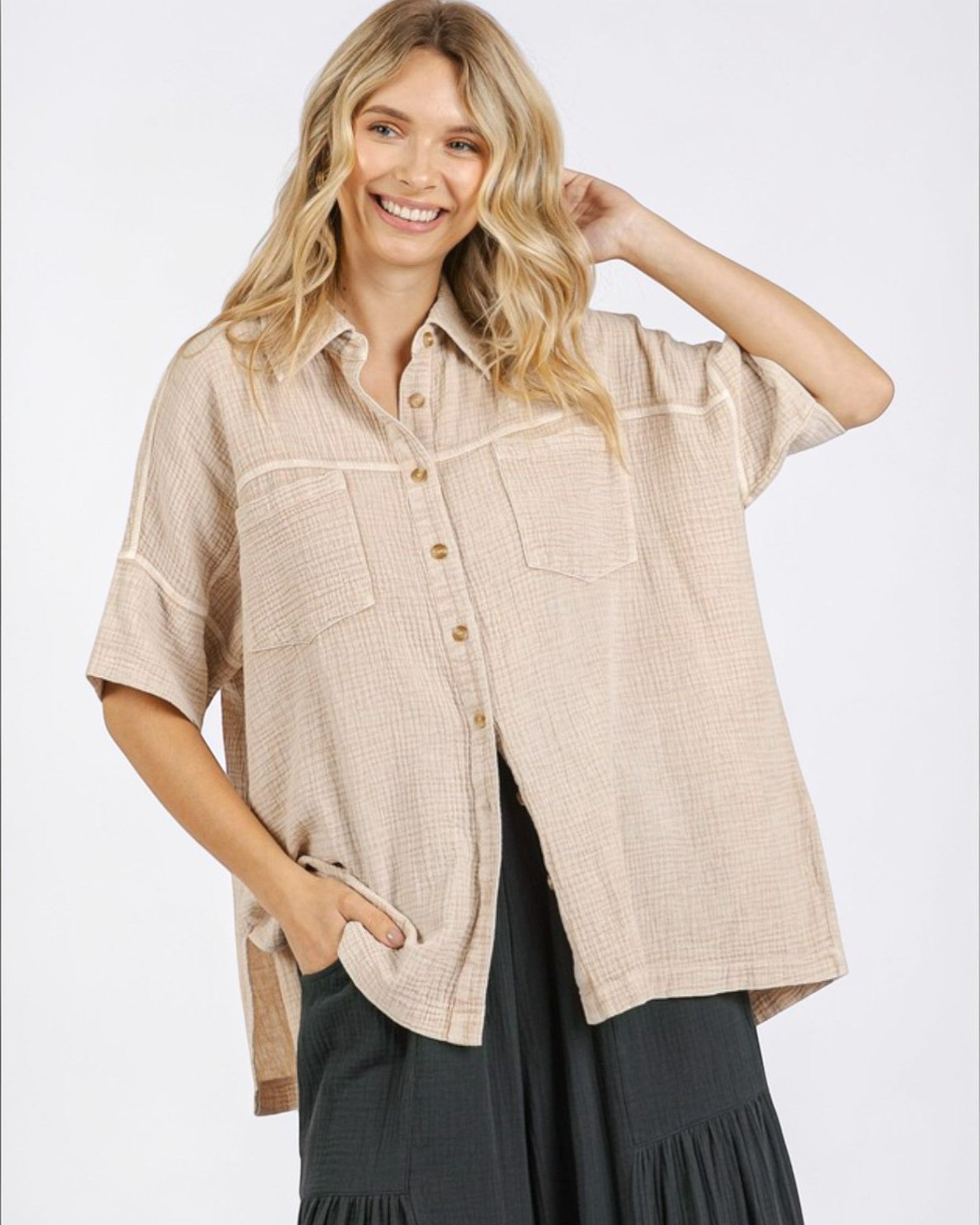 Woman wearing a beige button-up shirt with a white background