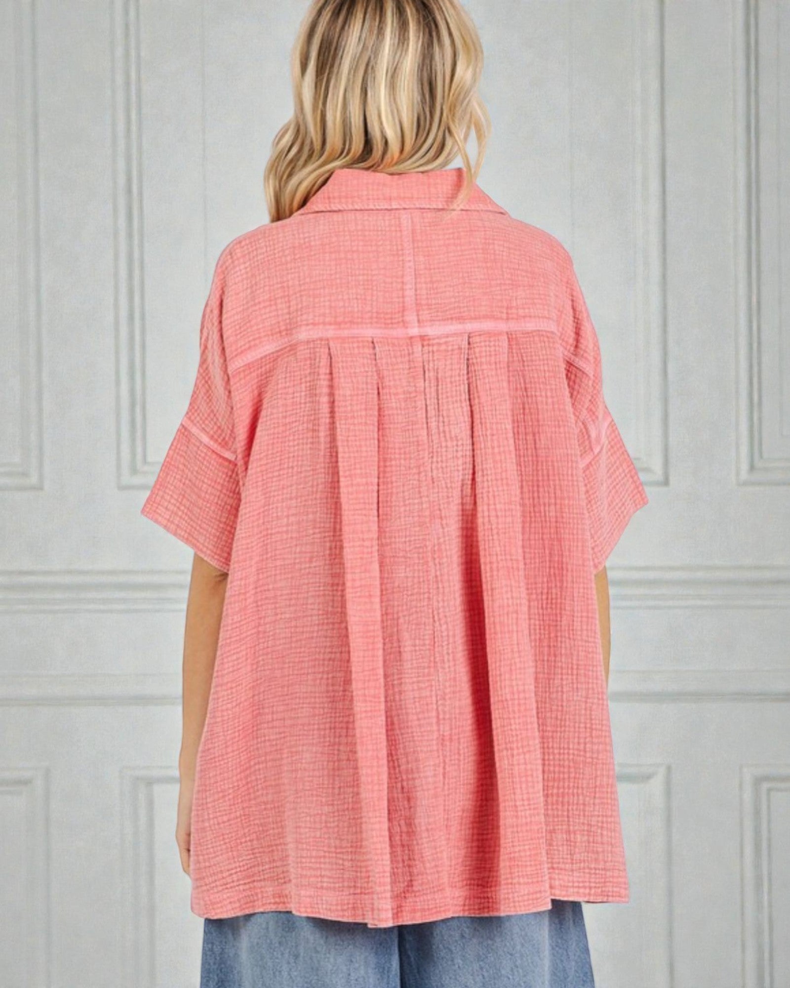 Person wearing a coral checkered shirt against a gray wall