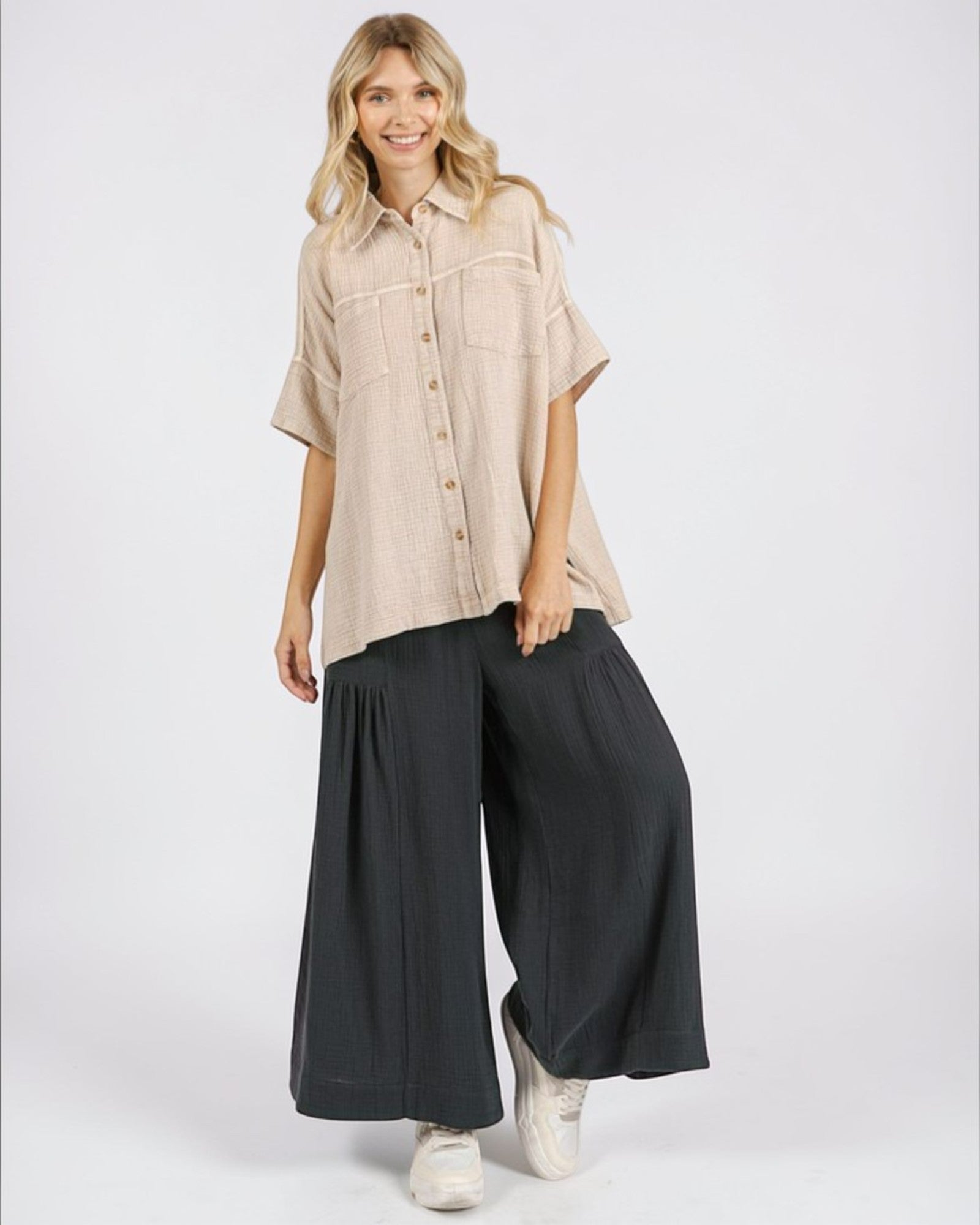 Woman wearing a beige shirt and black wide-leg pants on a white background