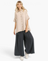 Beach Rose Co. sand cotton gauze oversized shirt with short sleeves, chest pockets, and button-down front on a model.
