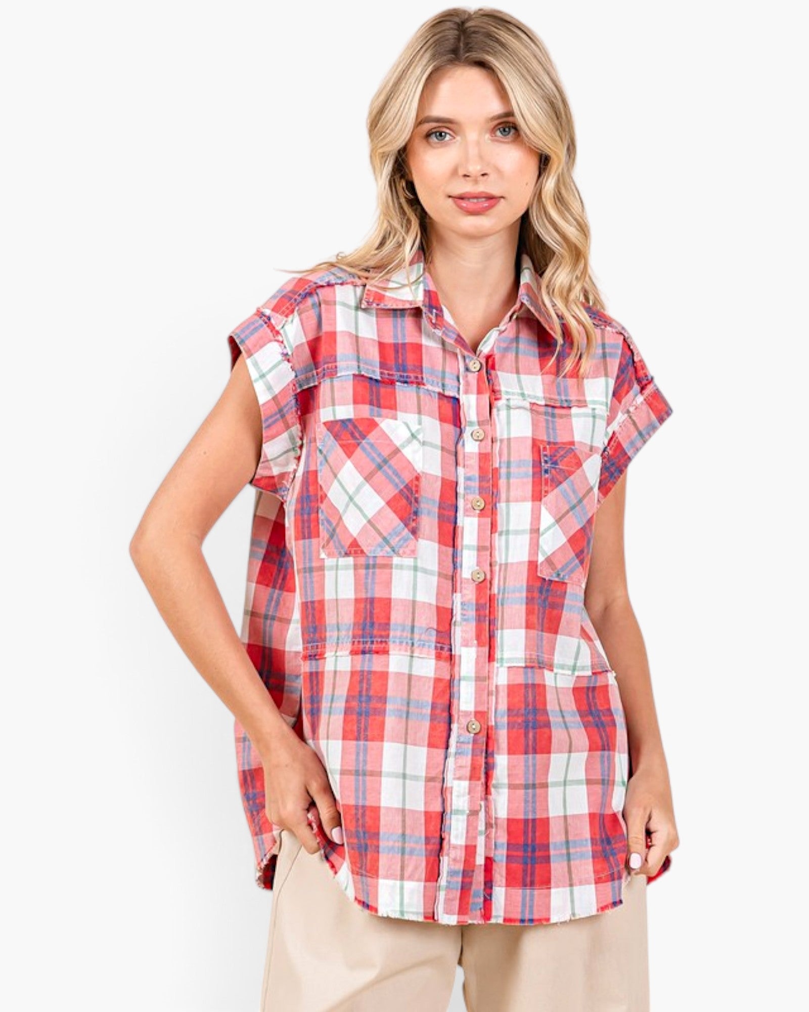 A woman modeling a red, white, and blue plaid short-sleeve button-up shirt with chest pockets, paired with beige pants, against a plain white background.