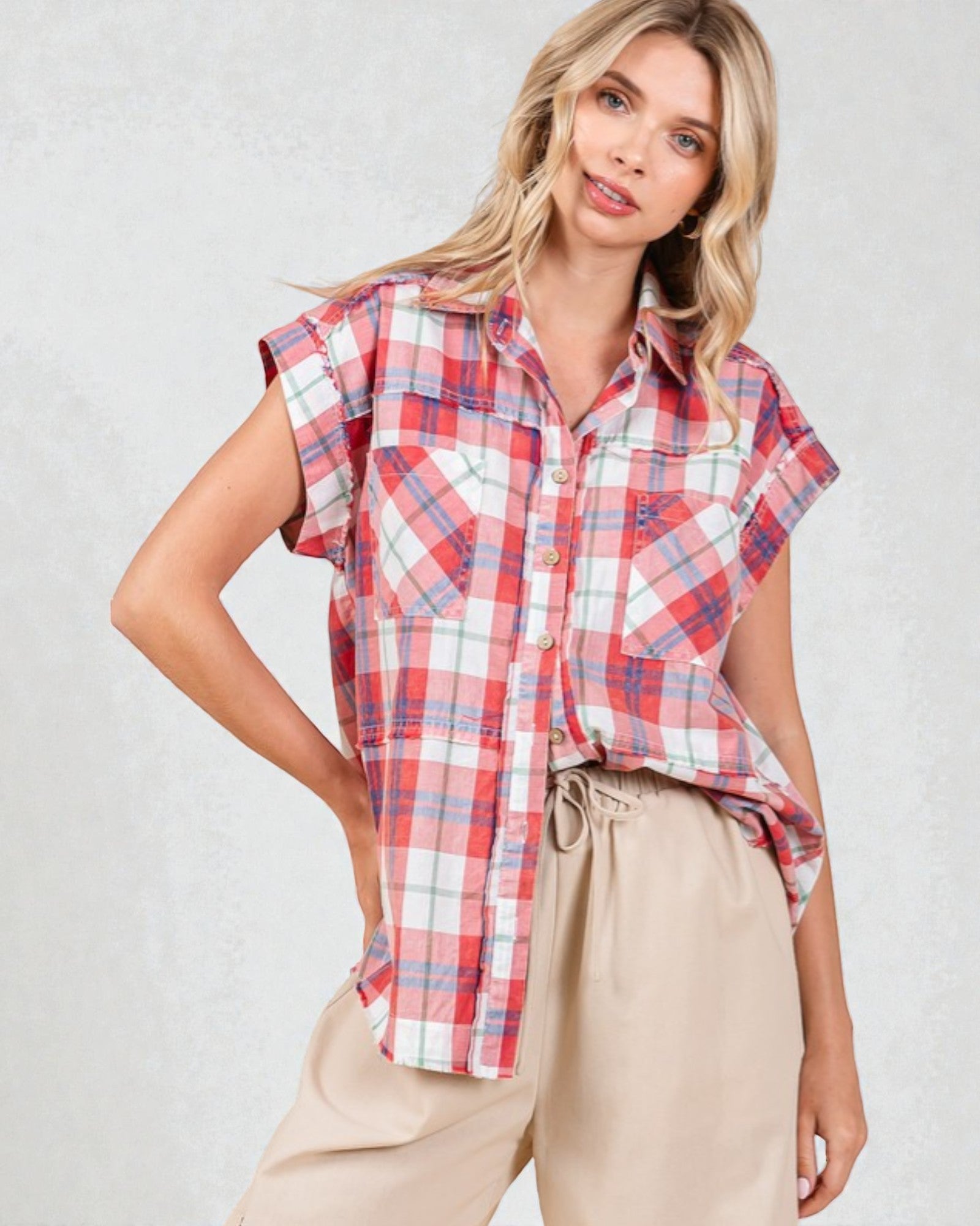 Woman wearing a red and white plaid shirt with beige pants on a light gray background