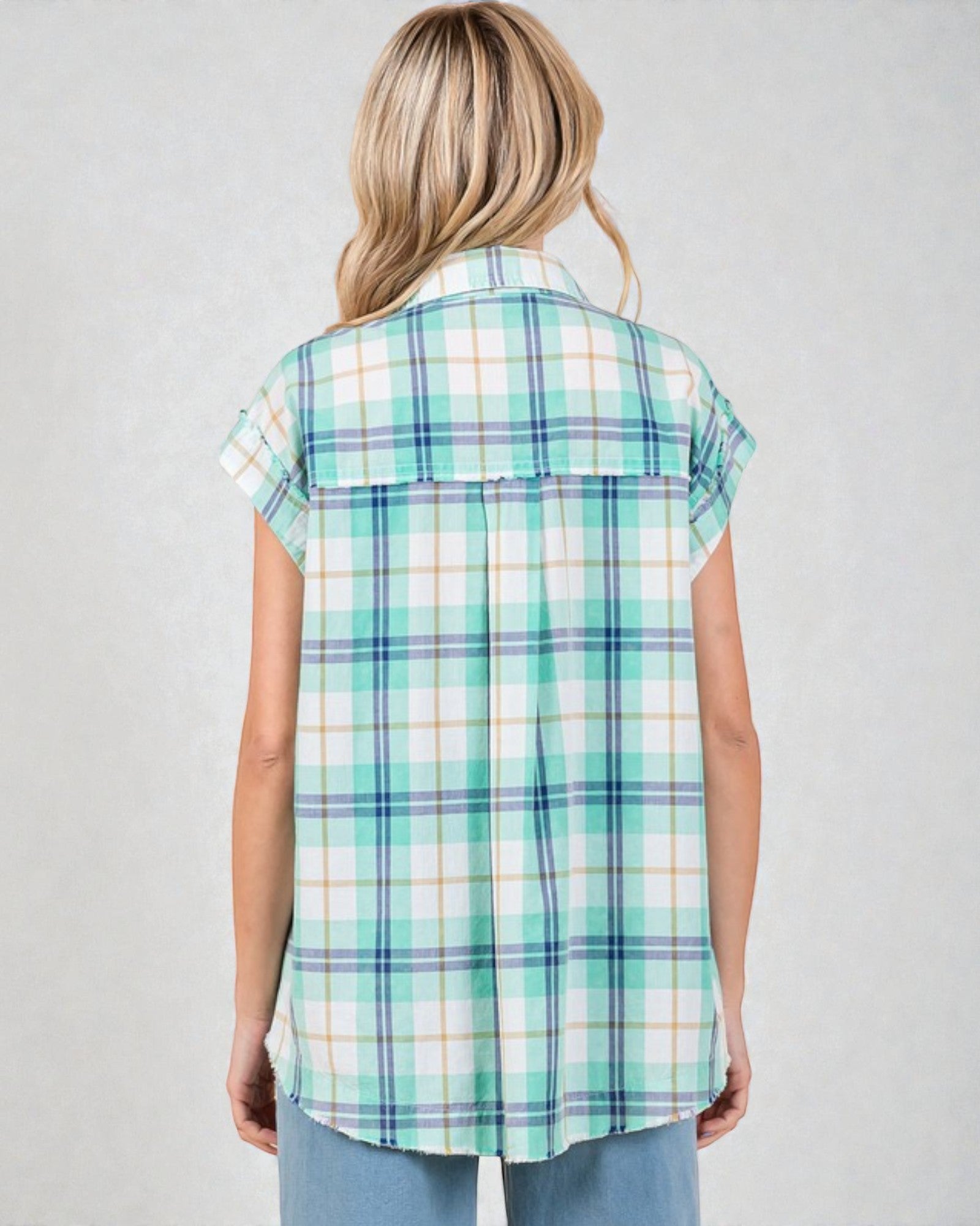 Woman wearing a green and white plaid shirt against a plain background