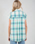 Woman wearing a green and white plaid shirt against a plain background
