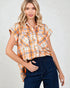 Woman wearing an orange and white plaid shirt with navy jeans on a light gray background