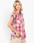 A woman wearing a red, white, and blue plaid short-sleeve button-up shirt, paired with beige pants, photographed against a clean white background.