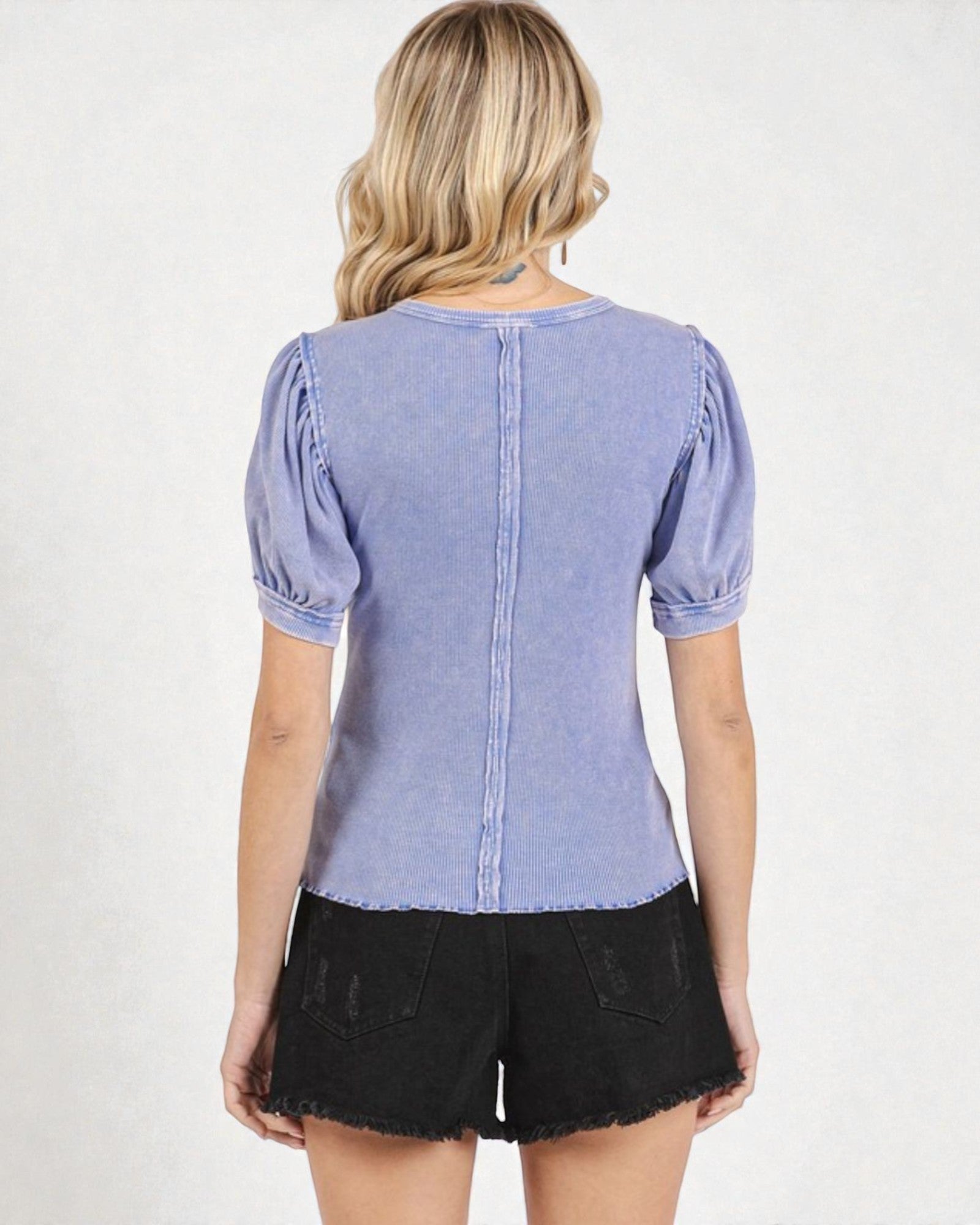 Woman wearing a blue denim top with puffed sleeves on a white background