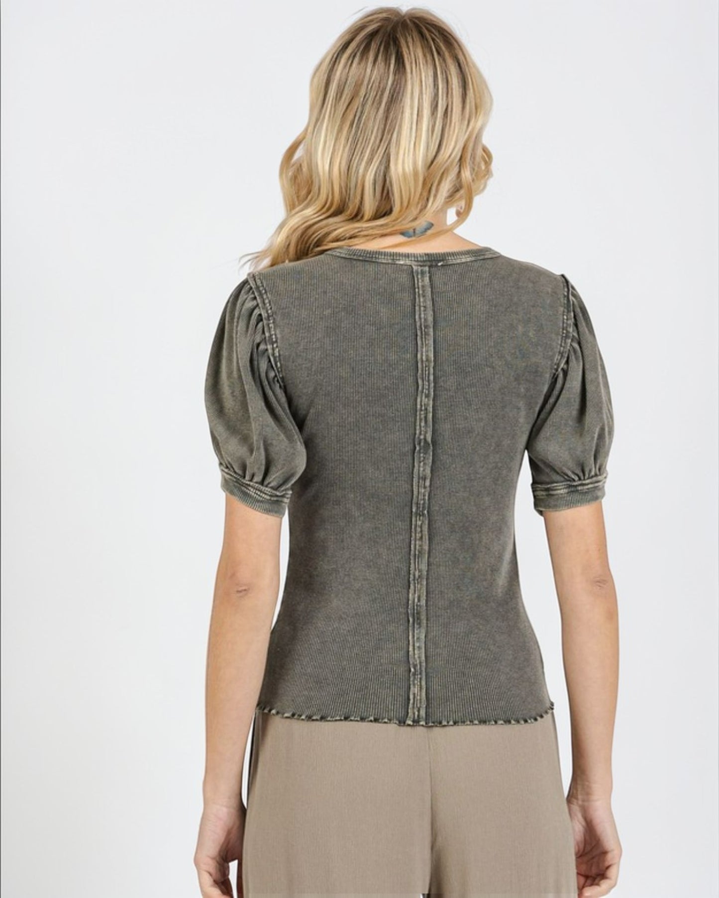 Woman wearing a green denim top with puff sleeves on a white background