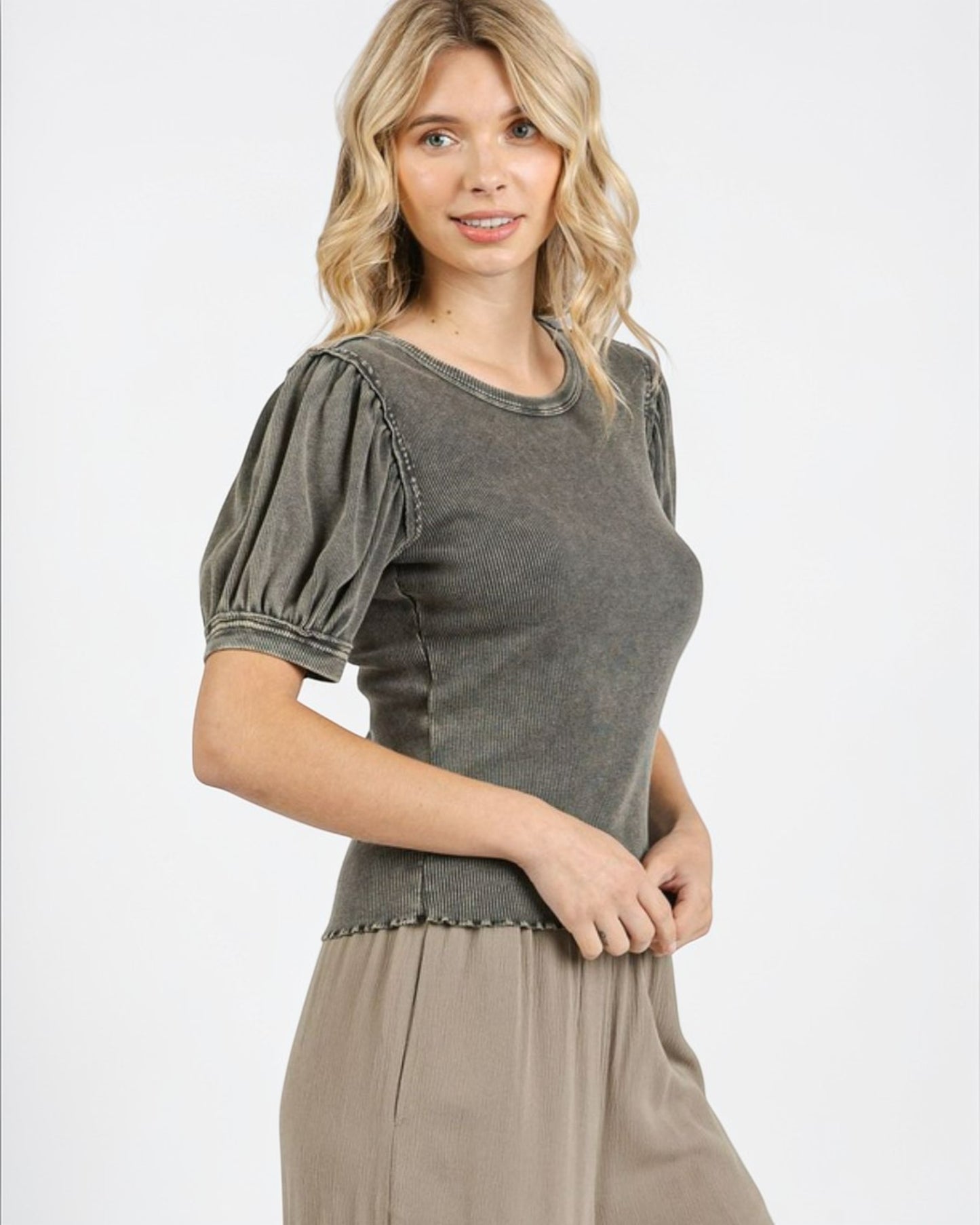 Woman wearing a gray top with puff sleeves on a white background