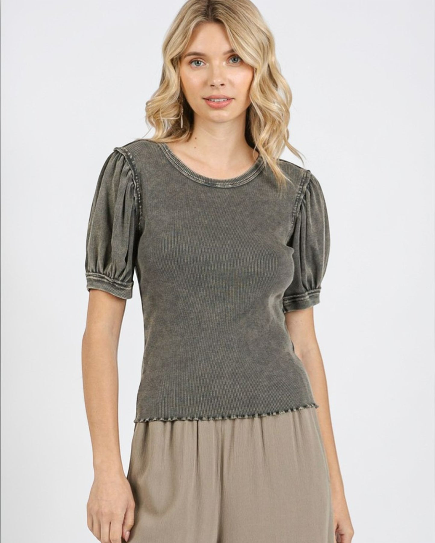 Woman wearing a gray top with puff sleeves on a white background