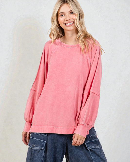 Woman wearing a pink oversized sweater and blue jeans against a white background