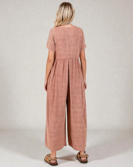 Woman wearing a pink checkered jumpsuit against a plain background