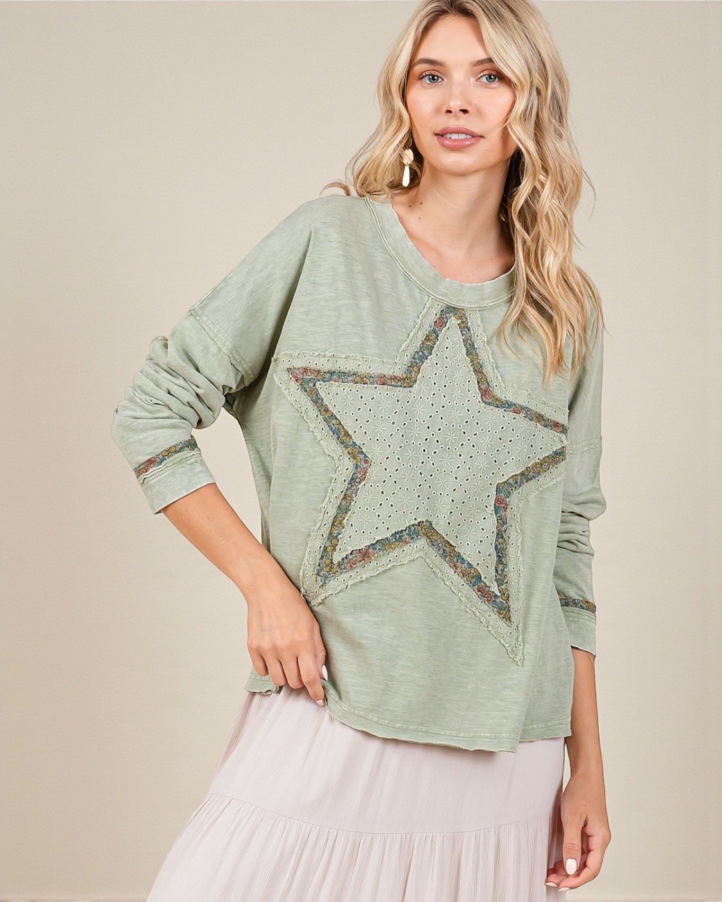 Woman wearing a green sweater with a star design on a beige background