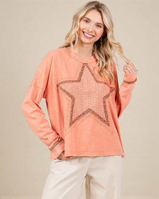 Woman wearing a coral long-sleeve top with a star design on a beige background