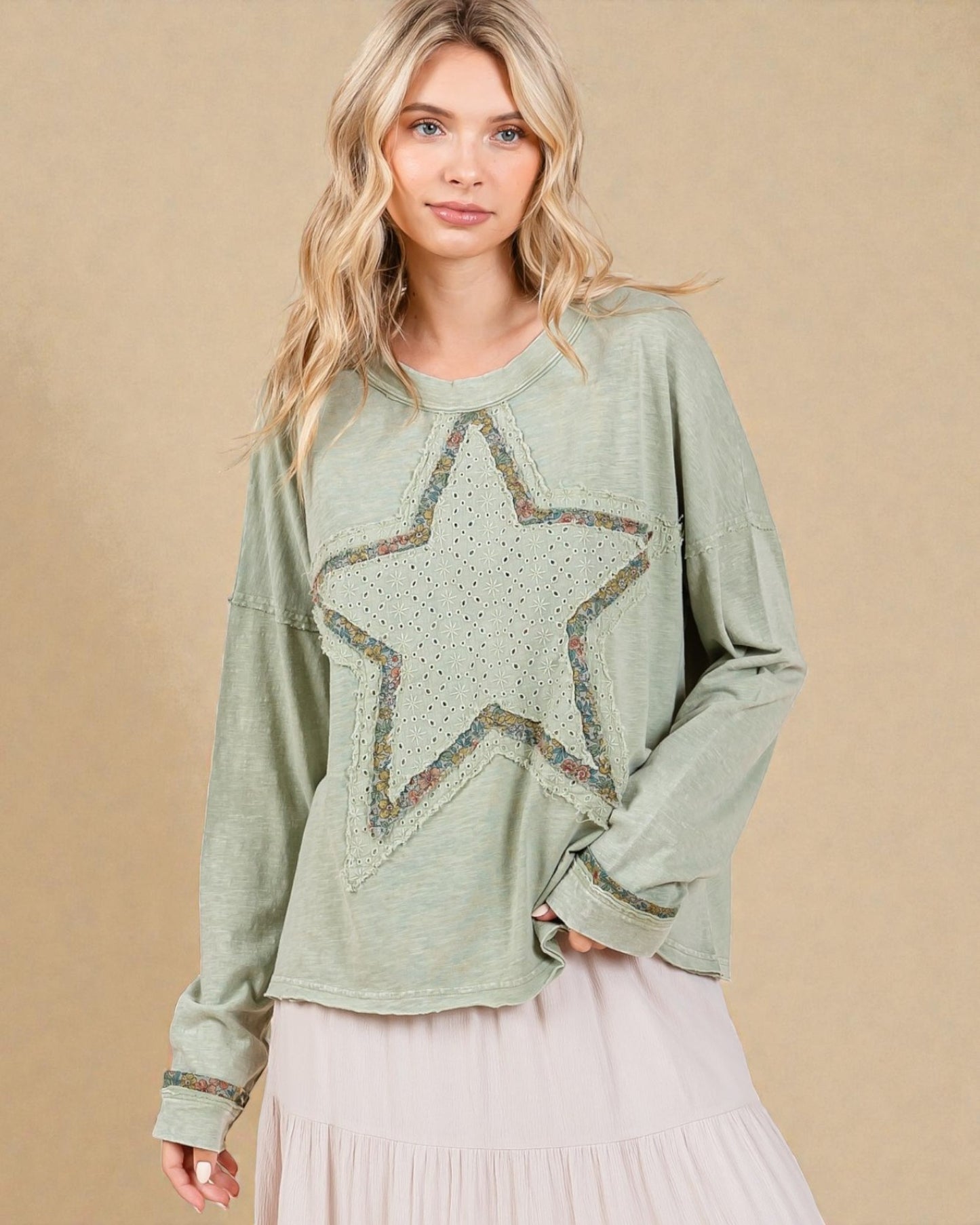 Woman wearing a green sweater with a star design on a beige background