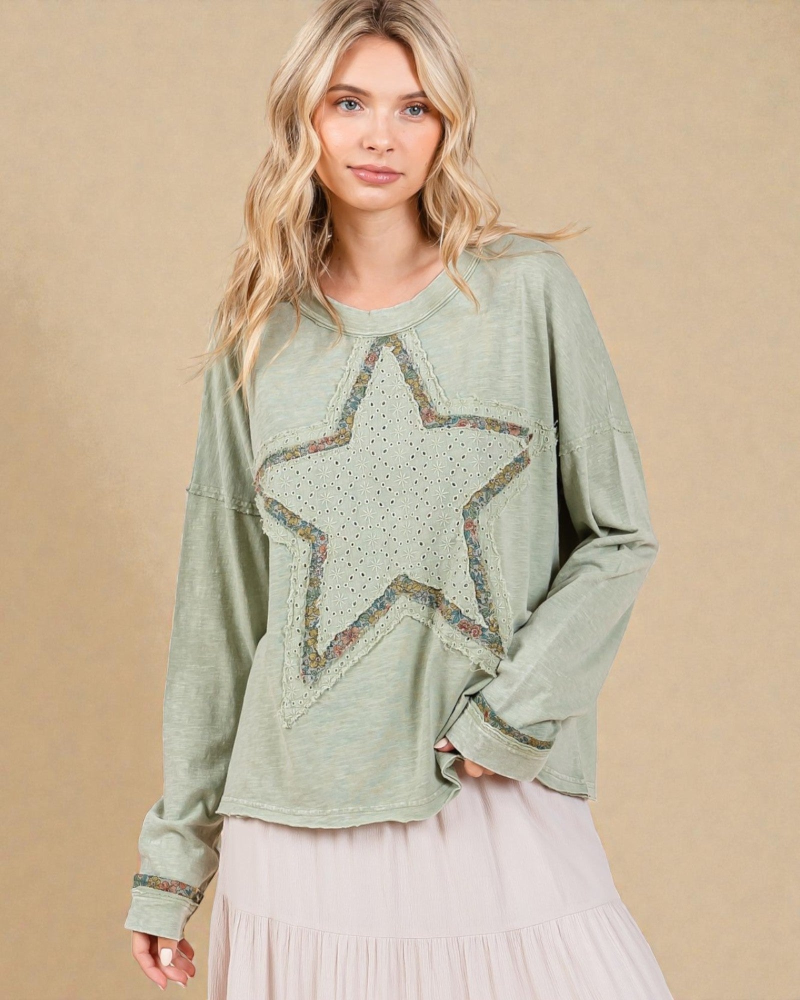 Woman wearing a green sweater with a star design on a beige background