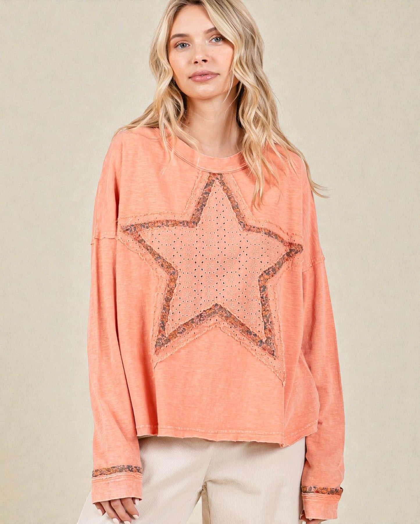 Woman wearing a peach-colored long-sleeve top with a star design on a beige background