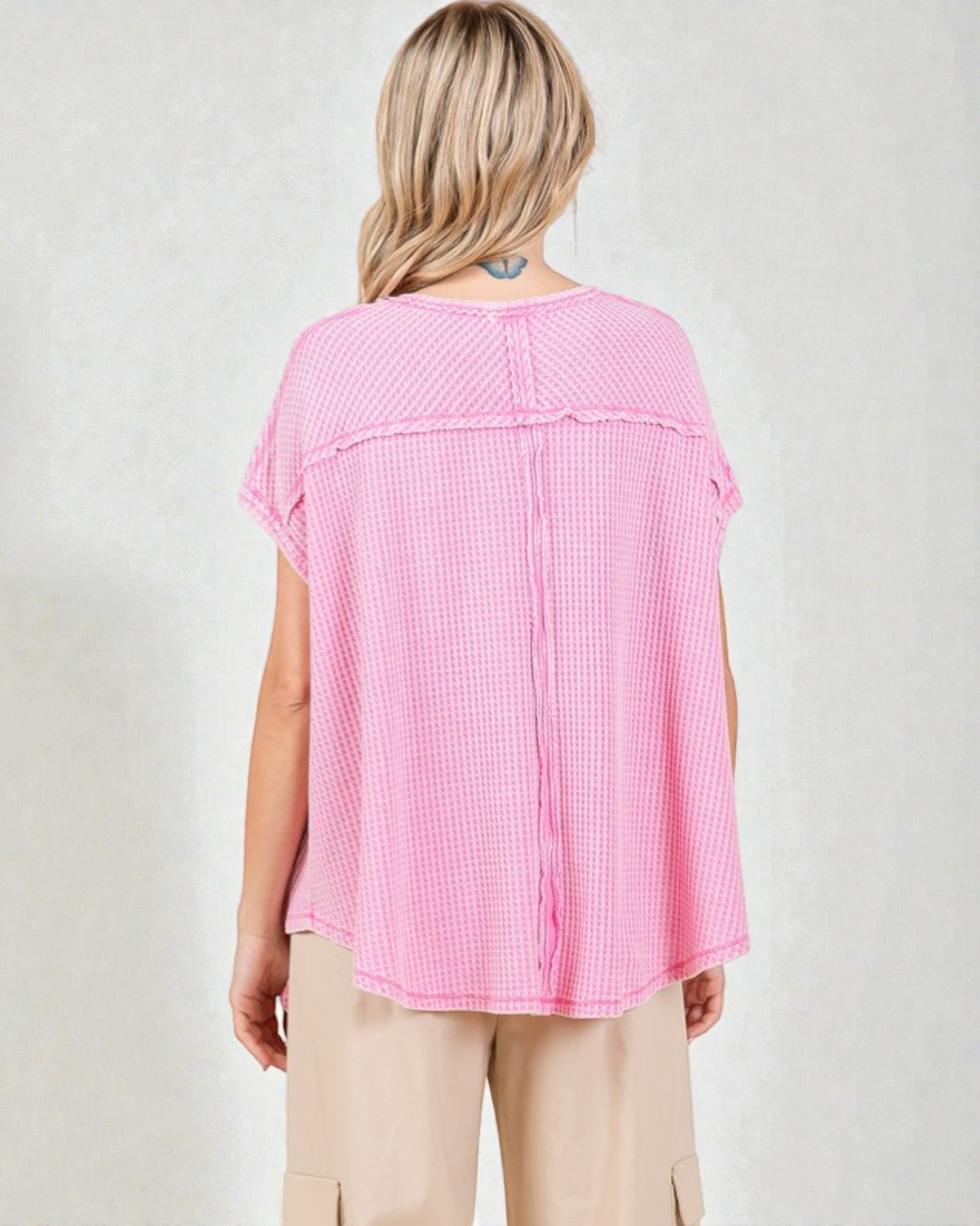 Person wearing a pink checkered top on a plain background