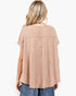A woman viewed from the back wearing a loose, short-sleeve waffle-knit top in a light peach-beige color, paired with blue jeans, against a plain white background.
