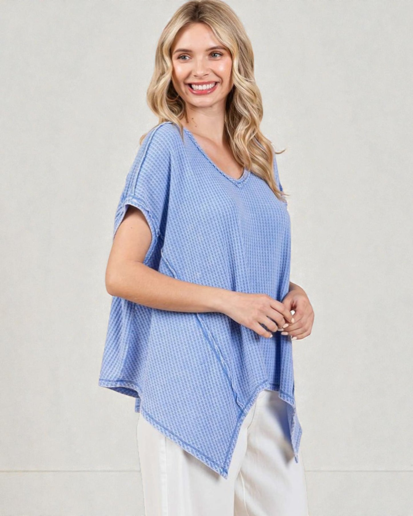 Woman wearing a blue checkered top with white pants on a light background