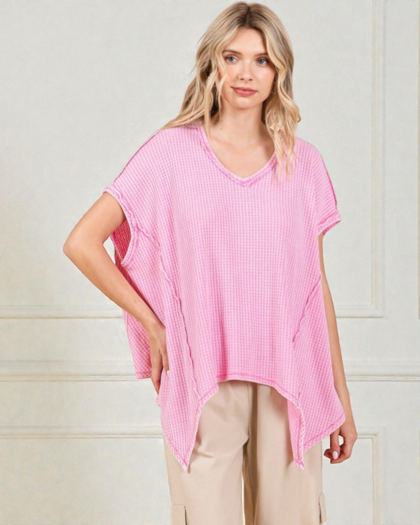 Woman wearing a pink poncho against a white background