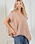 Woman wearing a beige textured top and blue jeans against a white background
