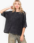 A woman modeling a washed black short-sleeve waffle-knit top with a chest pocket, paired with faded blue jeans, against a plain white background.