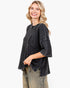 A woman modeling a dark charcoal gray waffle-knit cropped top with three-quarter sleeves and a front patch pocket, paired with distressed olive green pants, against a solid white background.