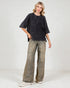 Woman wearing a black oversized shirt and wide-leg jeans on a white background