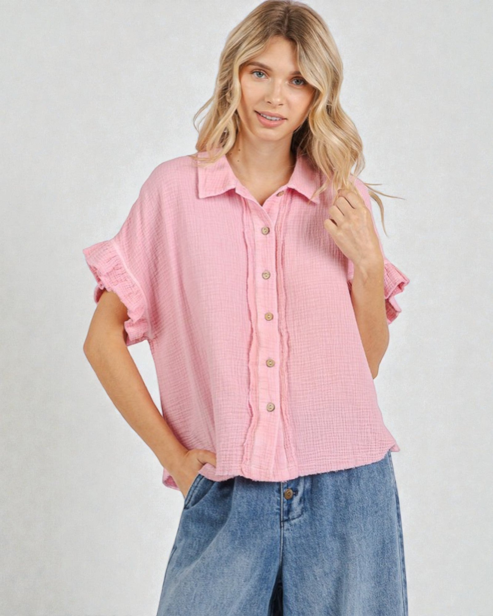 Woman wearing a pink checkered blouse with ruffled sleeves on a white background