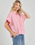 Woman wearing a pink blouse with ruffled sleeves on a plain background