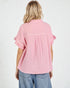 Person wearing a pink textured shirt with ruffled sleeves on a white background