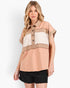 A woman modeling a short-sleeve color-block button-up shirt with peach, beige, and off-white panels, paired with black shorts, against a plain white studio background.