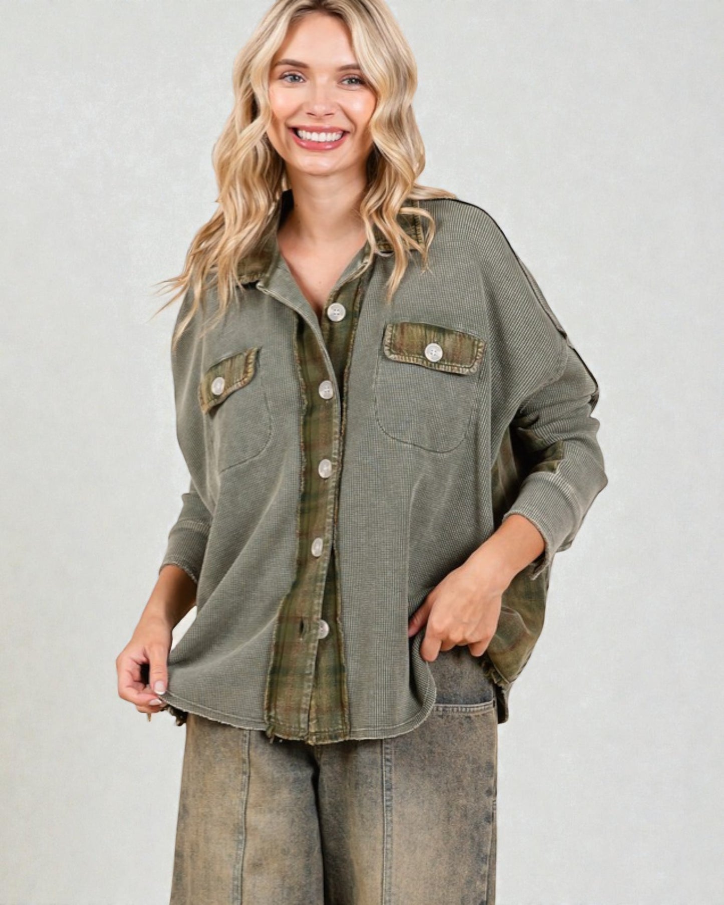 Woman wearing an olive green button-up shirt with rolled-up sleeves on a plain background