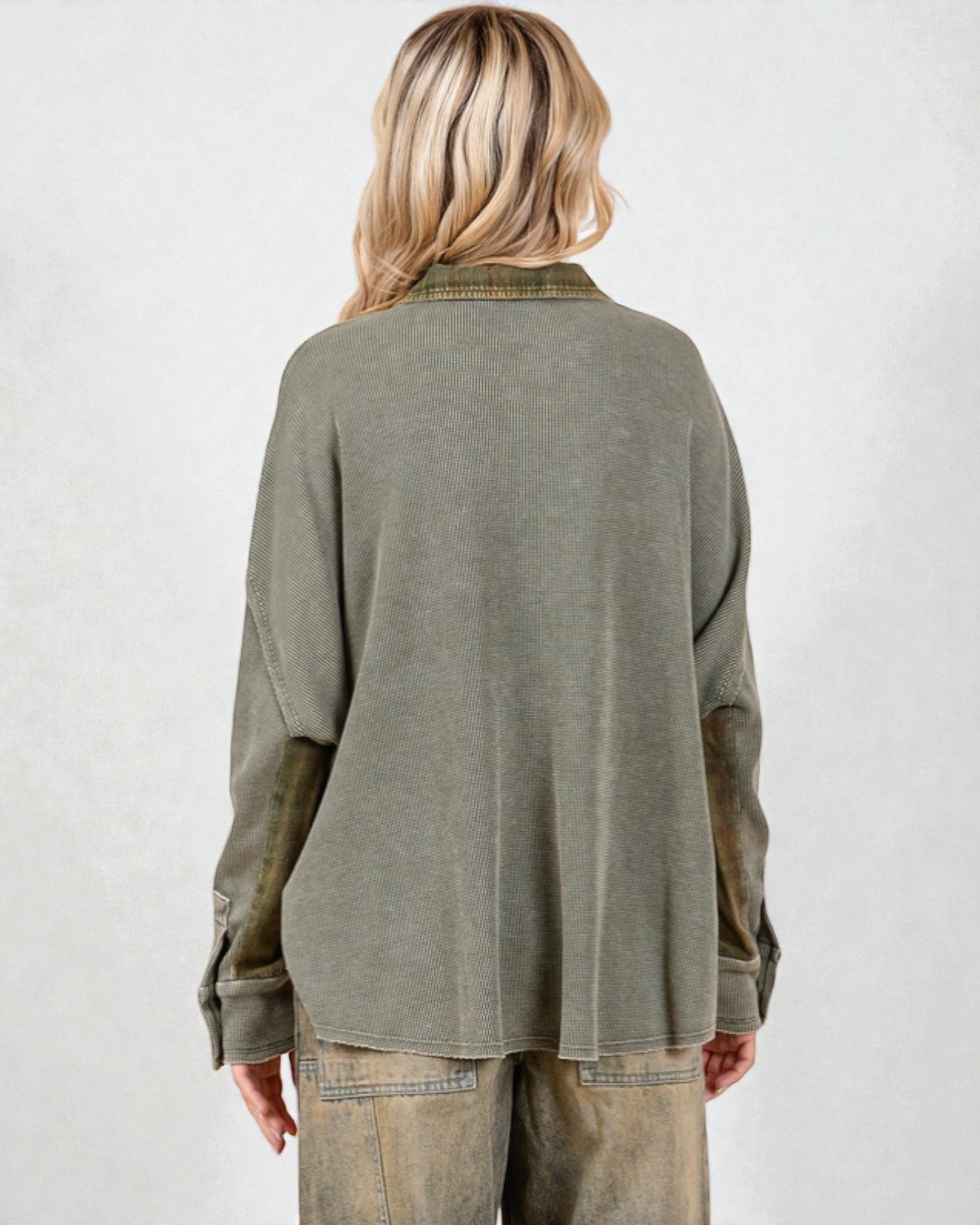 Person wearing an olive green long-sleeve shirt and beige pants on a white background