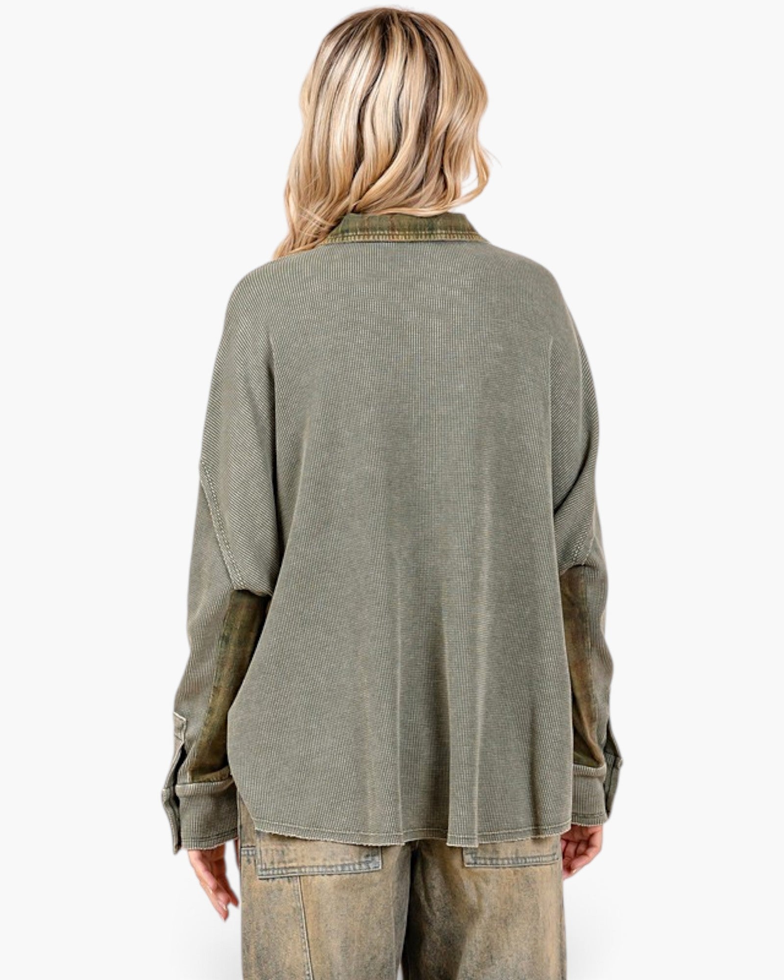 A woman shown from the back wearing a washed olive green long-sleeve shirt with distressed brown patches on the sleeves and light brown pants, against a plain white background.