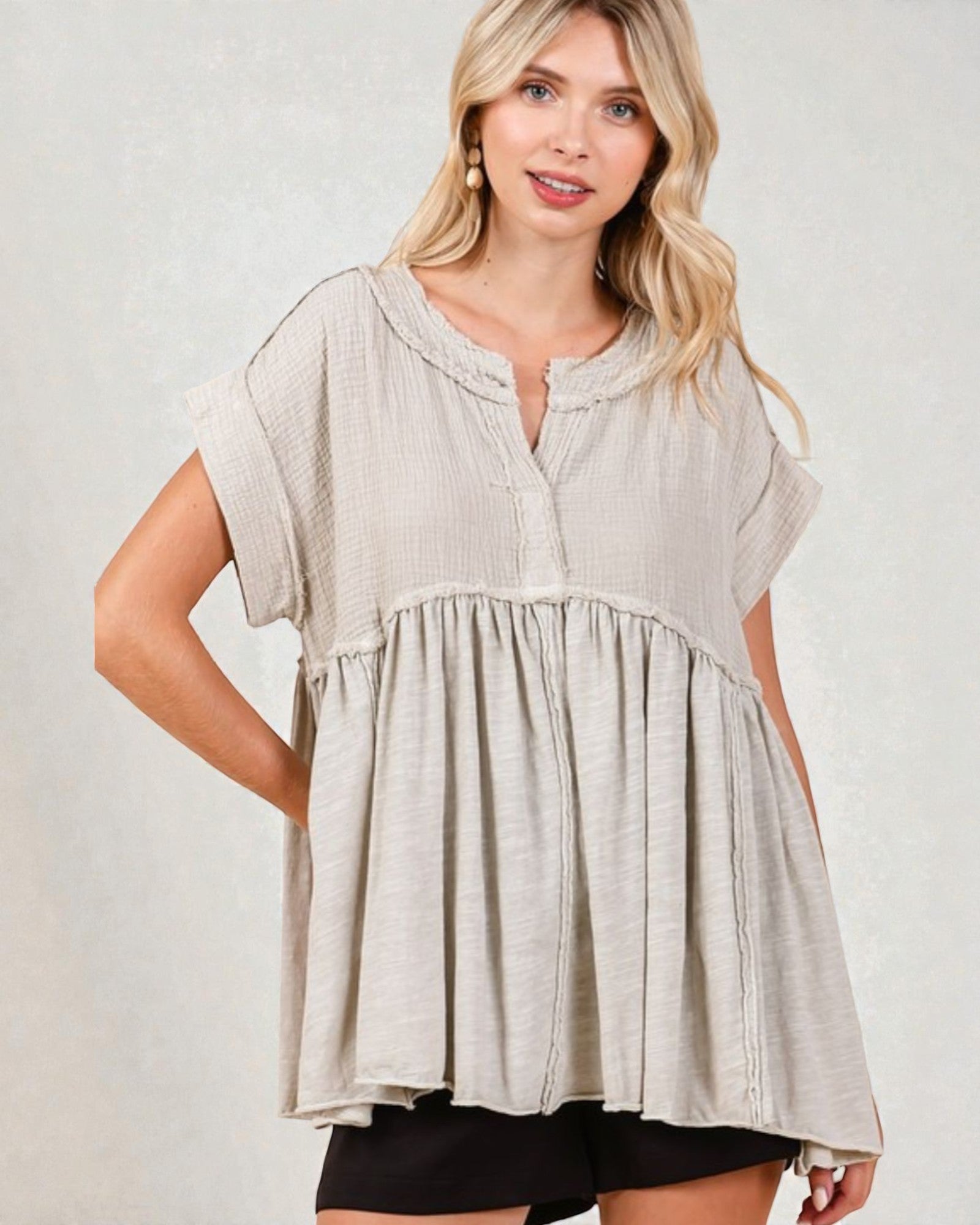 Woman wearing a beige short-sleeve top against a plain background