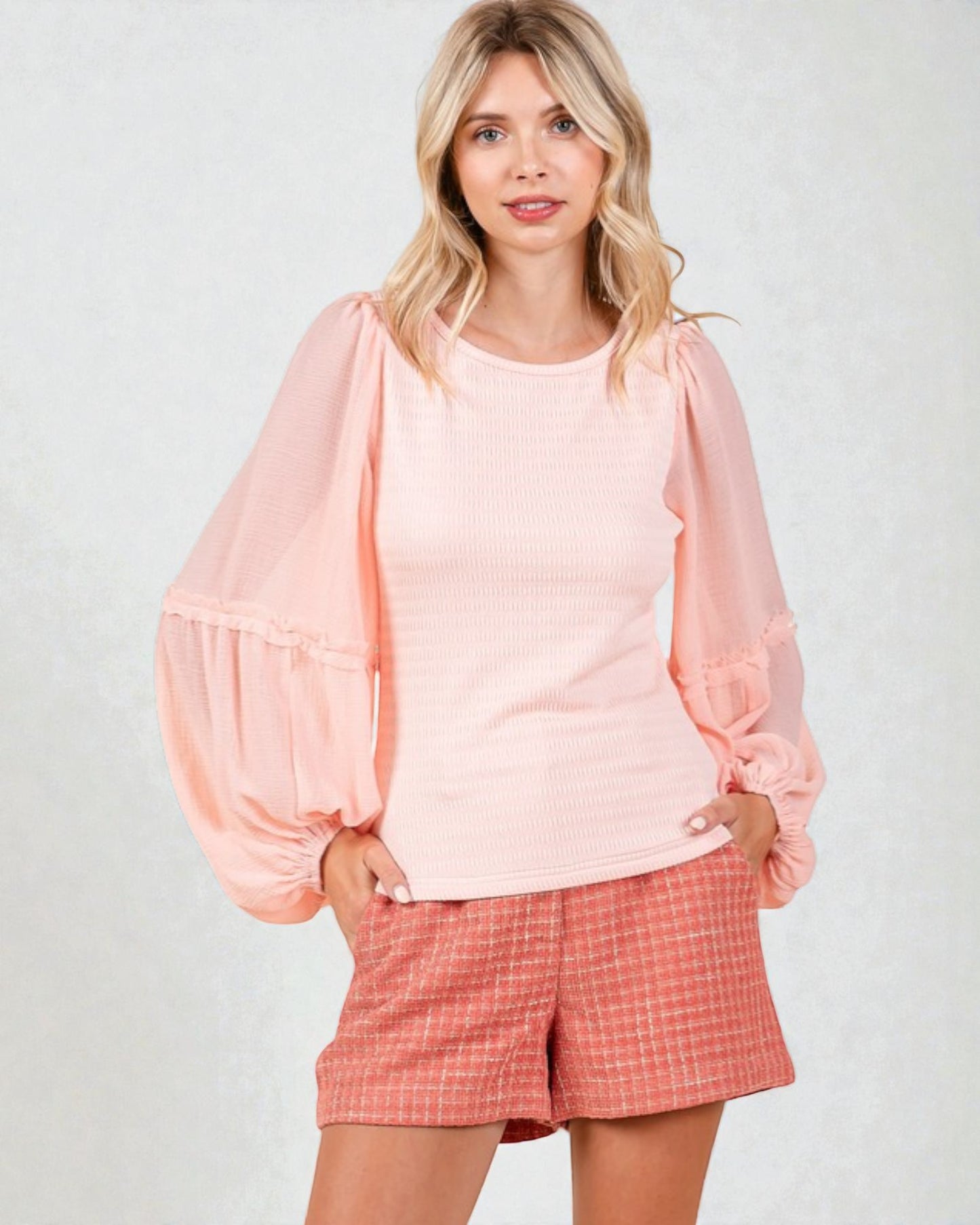 Woman wearing a pink top and checkered shorts on a light gray background