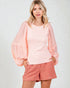 Woman wearing a pink top and checkered shorts on a light gray background