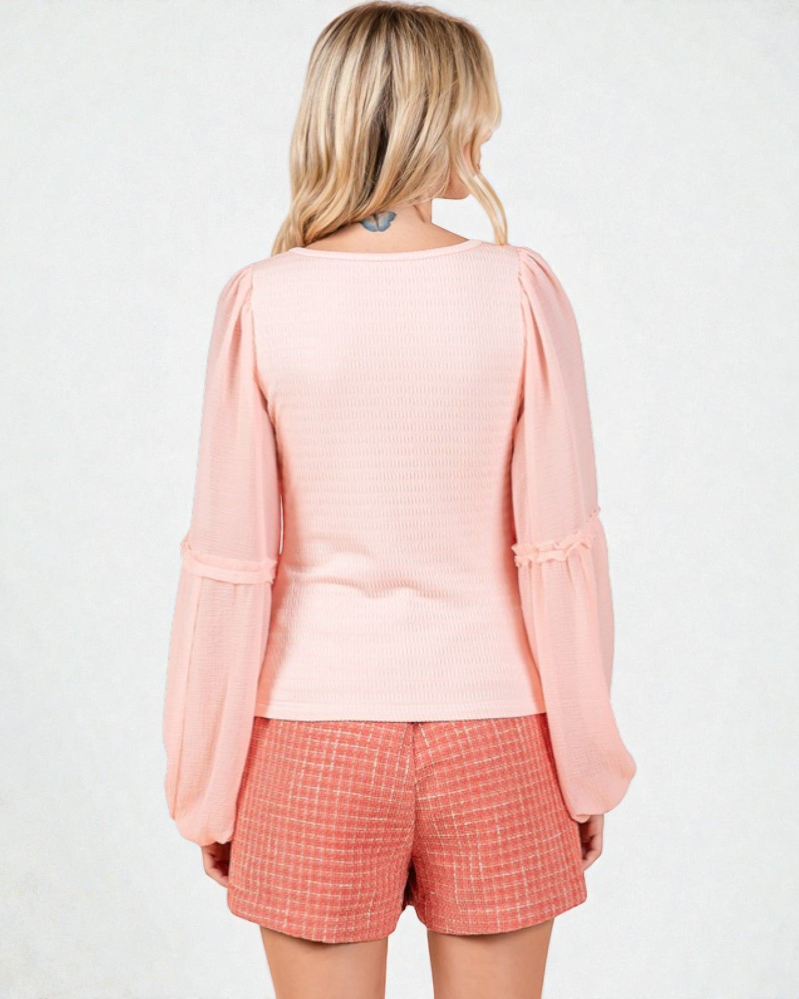 Woman wearing a pink top and checkered shorts on a white background